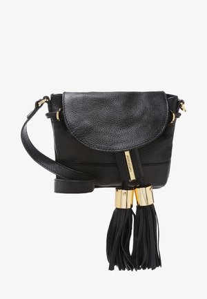 Sac bandoulière en cuir noir avec fermeture à rabat, ferrures dorées et deux longs pompons suspendus à la sangle avant.