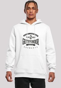 Hvid hættetrøje med et centralt sort grafisk motiv med teksten "Gryffindor Keeper" og "Quidditch Championship", en lomme foran og manchetter.
