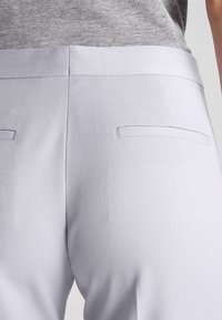 Light gray tailored trousers with a smooth texture, featuring two back pockets. The waistband is flat and the fabric has a subtle sheen.