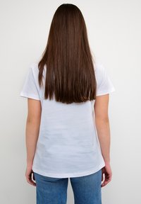 Hvid bomulds T-shirt med korte ærmer, rund halsudskæring og en afslappet pasform, parret med lyseblå denim jeans.