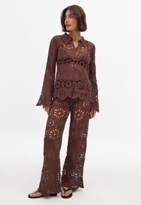 Set di top e pantaloni all'uncinetto marroni con motivo floreale, maniche lunghe, gambe svasate e design a rete. Tessuto leggero e textured.