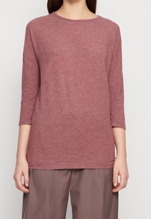 Maglietta a maniche lunghe color bordeaux realizzata in un tessuto morbido e strutturato con scollatura a girocollo. Presenta una vestibilità ampia e spacchi laterali all'orlo per facilitare i movimenti.