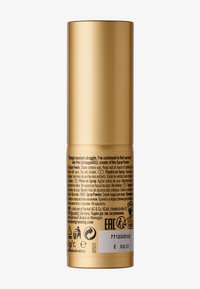 Guld cylindrisk spraybehållare med matt yta. Etiketten innehåller bruksanvisning och flerspråkiga varningsmeddelanden. Botten har återvinningssymboler.