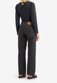 Czarne dżinsy z wysokim stanem, prostą nogawk�ą i klasycznym pięciopłatowym designem. Posiadają skórzaną naszywkę na plecach oraz delikatne detale w szwie.