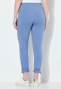 Blå bomullsleggings med en åtsittande design, som har spetst trimming i nederkant och ett elastiskt midjeband. Bärs med vita sneakers.