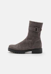Grå semsket ankelboot med rund tå, dekorativ søm på siden, og en stropp med en metallspenne ved ankelen. Rugged såle.