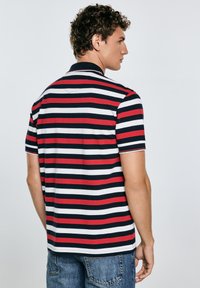 Polo majica s prugicami v mornariški modri, rdeči in beli barvi. Kratki rokavi, ovratnik in rebraste podrobnosti. Mehka tkanina z udobnim krojem.