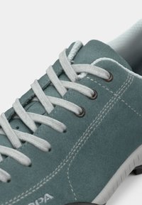 Teal semskinn-sneakers med hvite lisser, sølvøyer og gummisåle. Har sømdetaljer og en polstret krave for komfort.