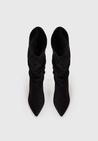 Bottes de cheville en daim noir avec un bout pointu et un design plissé, offrant une silhouette élégante et une texture lisse.
