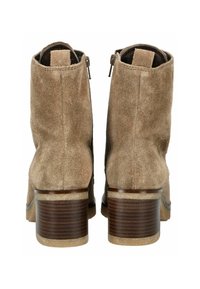 Bottines en daim marron avec une finition lisse, fermeture éclair sur le côté et un talon en bois avec des rayures horizontales.