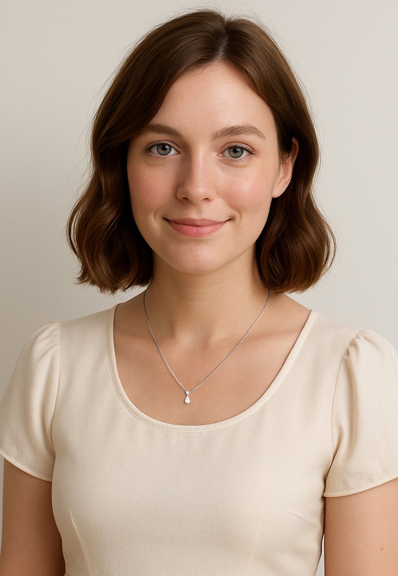 Sølv halskæde med en tårnformet vedhæng båret over en lys beige, kortærmet bluse med rund halsudskæring og glat tekstur.