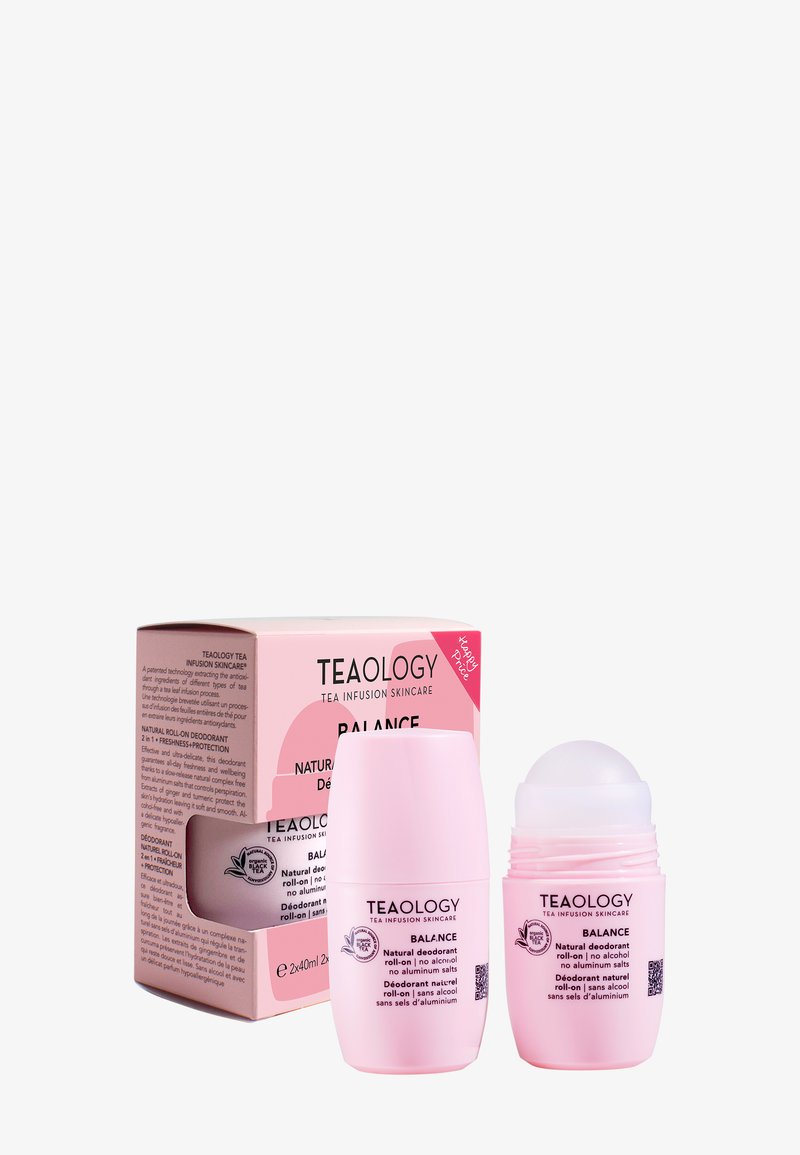 Twee roze Teaology Balance natuurlijke deodorant roll-ons, één met dop en één zonder dop, naast een bijpassende roze productdoos.