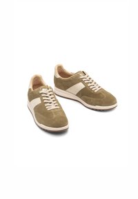 Sneakers in suede verde oliva con un design a righe bianche, lacci beige chiaro e suola marrone texturizzata. Punta arrotondata e collo imbottito.