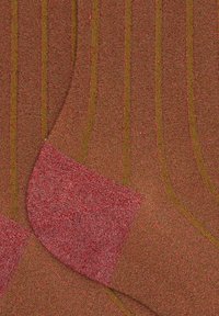 Calzini marroni con strisce verticali verdi e tallone e punta rossi. La texture è lavorata a maglia con una finitura leggermente rialzata e morbida.