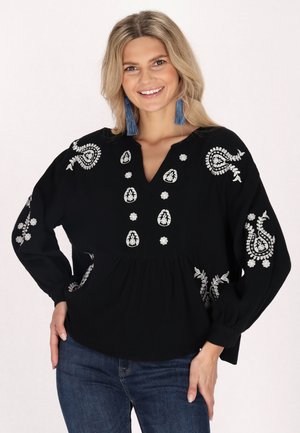 Zwarte blouse met lange mouwen, V-hals en ingewikkelde witte borduursels. Heeft een geraffineerde taille en knoopdetails aan de voorkant.