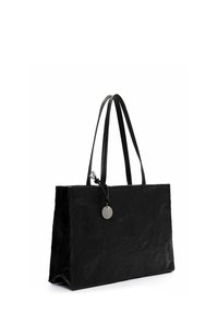 Borsa tote in pelle nera, di forma rettangolare, con texture liscia, due manici lunghi e un'etichetta metallica circolare attaccata.