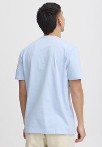 Lyseblå bomulls t-skjorte med rund hals og korte ermer. Stoffet har en glatt tekstur med minimal sømdetalj.