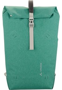 Sac à dos à rabat texturé vert avec sangle grise ajustable et boucle, présentant un logo discret et des points d'attache latéraux.