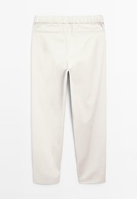 Pantaloni beige chiaro con cintura elasticizzata e due tasche a filetto posteriori, disposti piatti su uno sfondo bianco.
