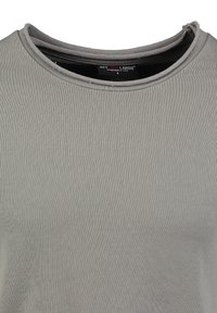 Grau geripptes Kurzarmshirt mit Rundhalsausschnitt, das subtiler Textur und einem unvollendeten Saumdetail am Kragen aufweist. Markenlabel sichtbar im Inneren.
