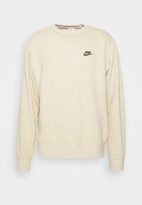 Béžová mikina vyrobená z texturované tkaniny se skvrnami. Má kulatý výstřih a malé černé logo Nike na hrudi.