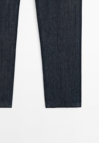 Jeans in denim blu scuro esposti su uno sfondo bianco, evidenziando il taglio dritto e le cuciture pulite. Adatti per un look casual.