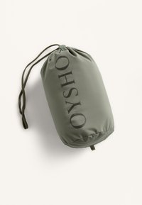 Trekkoord pouch in olijfgroen stof, met het woord "OHSO" in zwarte, vetgedrukte letters. Glad textuur, cilindervorm, afgesloten met een togglesluiting.