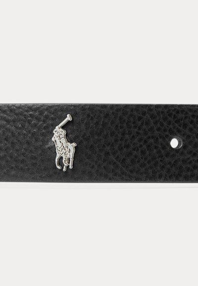 Fekete, texturált bőrből készült övszegmens ezüstszínű polo játékos emblémával és egyetlen lyukkal egy fehér háttéren.