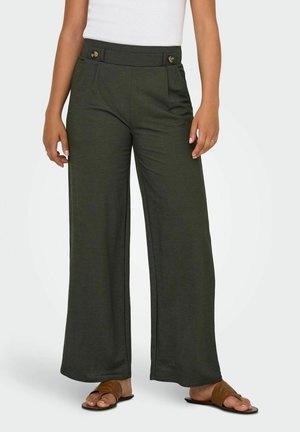 Femme portant un pantalon vert foncé taille haute à jambes larges avec des détails de ceinture boutonnée et des sandales plates marron.