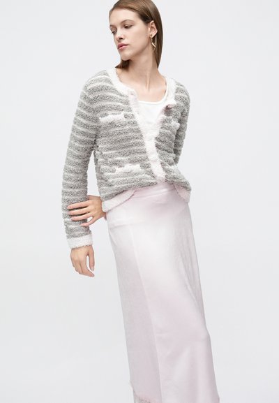 Šedý a bílý proužkovaný svetr s jemnou, nadýchanou texturou, s výstřihem do V a růžovým lemováním, doplněný světle růžovou saténovou sukní.