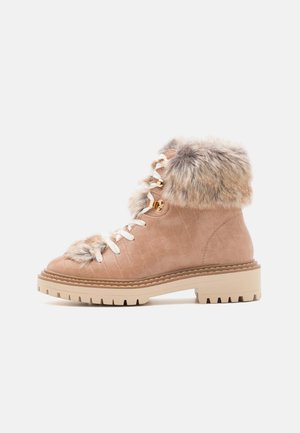 Bottines à lacets en cuir beige clair avec un col en fourrure douce, surface texturée et semelle en caoutchouc crème robuste.