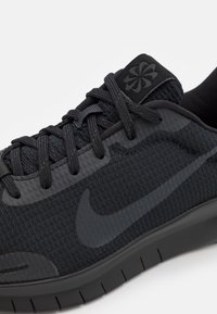 Musta urheilukenkä, jossa on teksturoitu ja hengittävä upeus, sulavalinjainen, kiiltävä swoosh-logo, teksturoituneet nauhat ja joustava kumipohja.