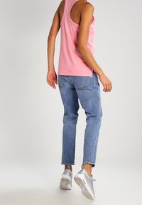 Ljusa rosa linne, blå denimjeans med avslappnad passform och silverfärgade sportskor med texturerad yta. En enkel och avslappnad outfit.