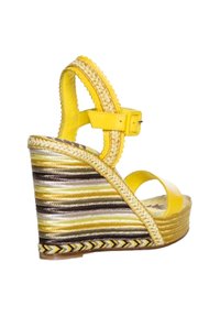 Sandalia cuña amarilla con dos tiras en los dedos y una tira en el tobillo. El tacón tejido textura presenta franjas amarillas, marrones y blancas. Cierre con hebilla.