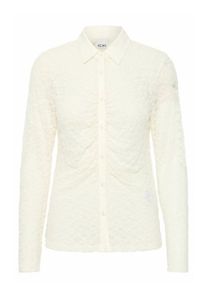 Long-sleeve, cream-colored blouse with a textured lace pattern, featuring a button-down front and a classic collar. Soft, sheer fabric.