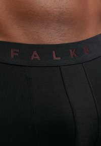 Boxers en coton extensible noir avec une ceinture texturée portant le nom "FALKE" en couleur bordeaux. Fini lisse, design ajusté.