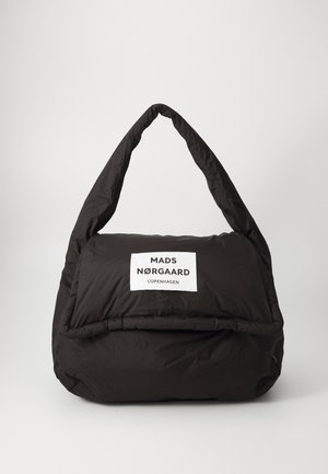 Zwarte gewatteerde tas met een opvallend wit label met "MADS NØRGAARD COPENHAGEN." Kenmerkende gebogen handgreep en zachte textuur.