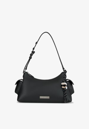 Melna ādas rokassoma ar īsu regulējamu siksnu, sānu kabatām, sudraba logotipa plāksni un raksturu atslēgu piekariņu ar saulesbrillēm un baltām matiem.