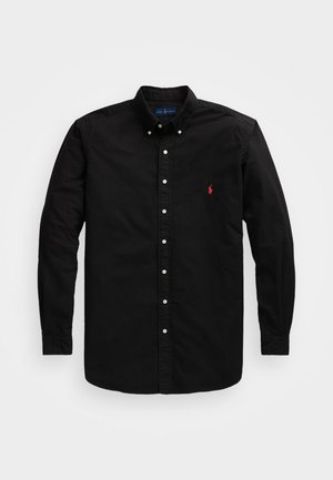 Camisa preta de manga longa feita de algodão, com colarinho clássico, fecho frontal com botões e um pequeno logotipo vermelho no lado esquerdo do peito.