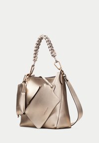 Metallic guldhandväska med en strukturerad yta, en flätad topphandtag och en bifogad zip-påse. Inkluderar ett avtagbart axelband.