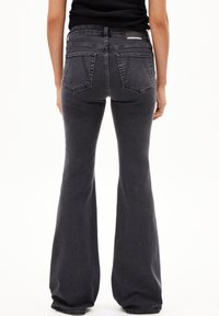 Zwarte flared jeans met een hoge taille, kenmerkend door een gladde textuur, twee achterzakken en een subtiele vervaagde uitstraling.