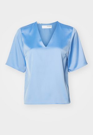 Blouse en satin bleu clair avec un décolleté en V, des manches courtes et une texture lisse, présentant une coupe relaxée et des détails de couture minimalistes.