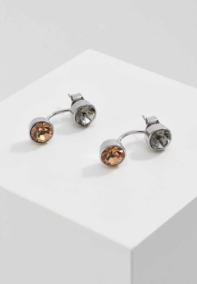 Paire de jackets d’oreilles ton argent avec une pierre précieuse ronde facettée claire et une ambre sur chaque boucle d’oreille, présentées sur une surface blanche.