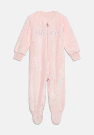 Body bébé rose doux avec manches longues, poignets ajustés, couvre-pieds, fermeture éclair à l'avant et logo "GUESS" sur la poitrine en lettres blanches.