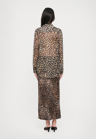 Sheer leopard print maxi dress and long-sleeve top set; beige and brown tones, with a fluid texture and an open back design.