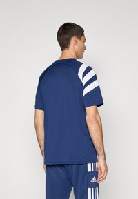 Camiseta deportiva de color navy con franjas blancas en los hombros, mangas cortas y cuello redondo. Tela suave, corte relajado.