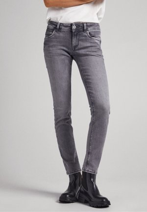 Jeans ajustados gris hechos de mezclilla, con un diseño de cinco bolsillos, detalles de costura y una silueta entallada, combinados con botas negras hasta el tobillo.