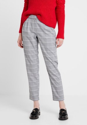Pantalons à carreaux gris avec une coupe ajustée, dotés de plis à l'avant et d'une texture lisse. Associés avec un pull en maille rouge et des mocassins noirs.