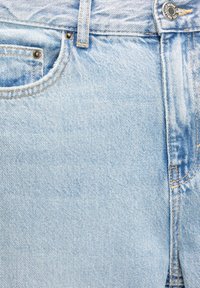 Shorts din denim de culoare albastru deschis, cu un model decolorat, având o buzunar frontal, două rădăcini metalice și cusături vizibile la talie și pe cusăturile laterale.