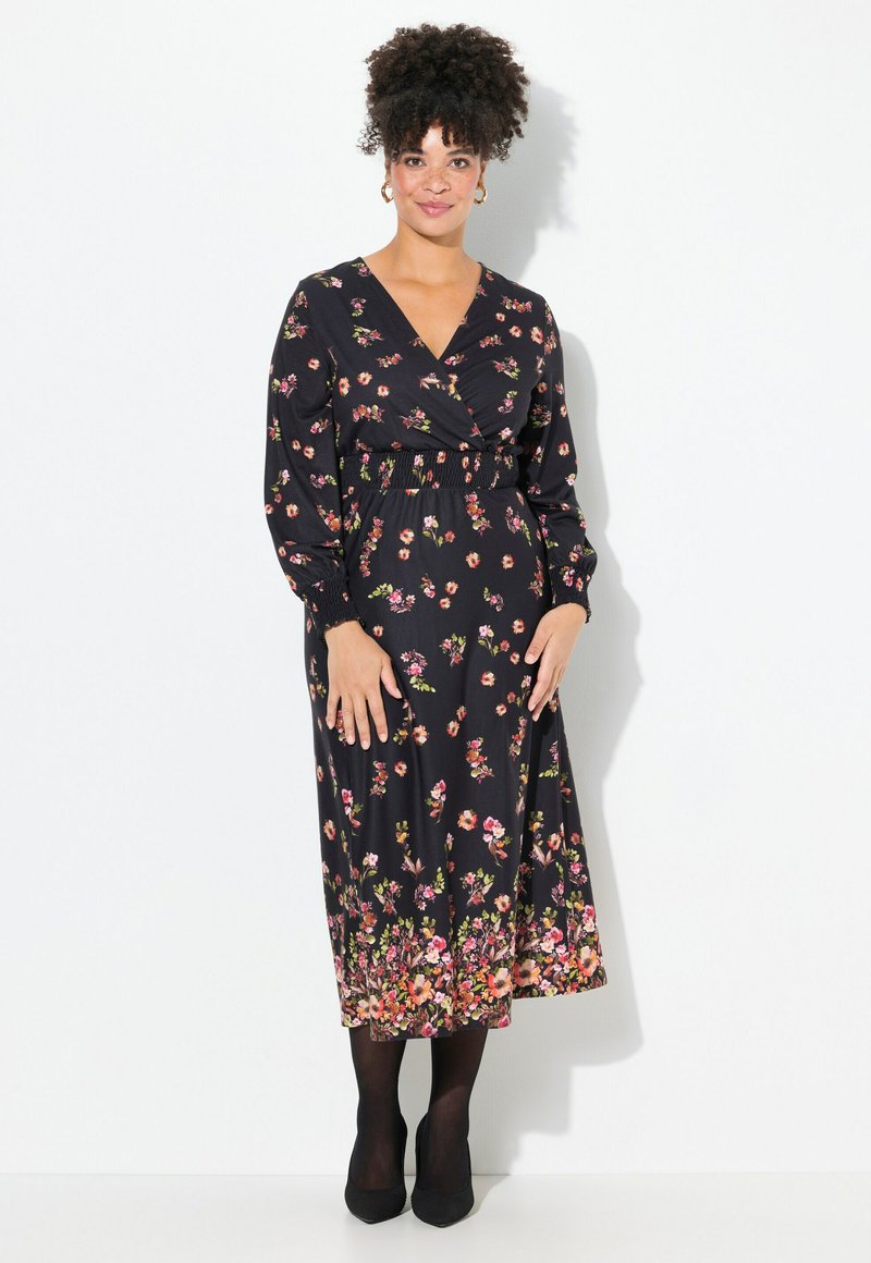 Schwarz gemustertes Wickeldress mit langen Ärmeln, das eine geraffte Taille, zarte rosa und grüne Blumenmuster sowie einen fließenden Saum aufweist.